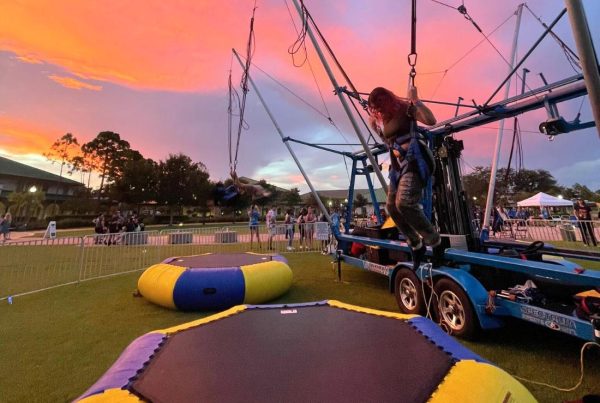 Woman jumping on bungee rental in sunset