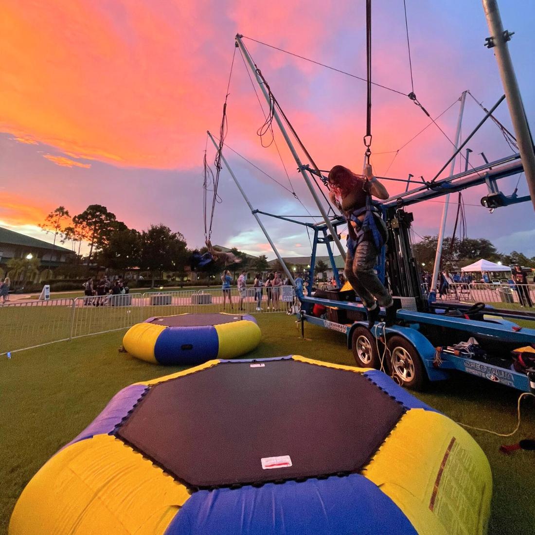 Woman jumping on bungee rental in sunset