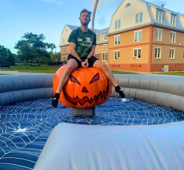 Male riding the mechanical pumpkin ride rental outdoors